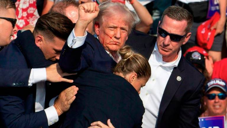 Republican candidate Donald Trump is seen with blood on his face surrounded by secret service agents as he is taken off the stage at a campaign event at Butler Farm Show Inc in Butler, Pennsylvania, July 13, 2024. -AFPpix