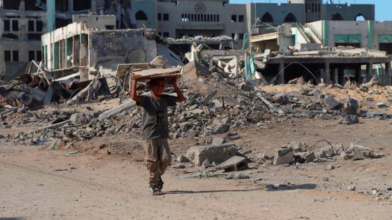 A Palestinian boy walks carrying a piece of wood board, amid a ceasefire between Israel and Hamas, in Gaza City, October 16, 2025. - REUTERSPIX