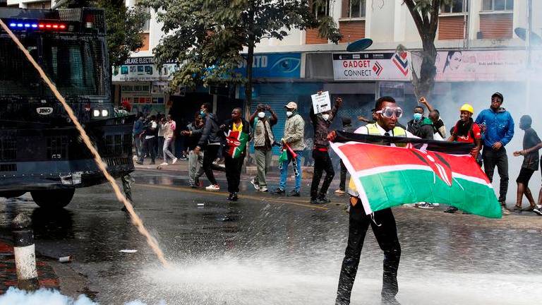 A demonstrator holds a Kenyan flag as police use water cannons and tear gas to disperse protesters during a demonstration against Kenya's proposed finance bill 2024/2025 in Nairobi - REUTERSpix