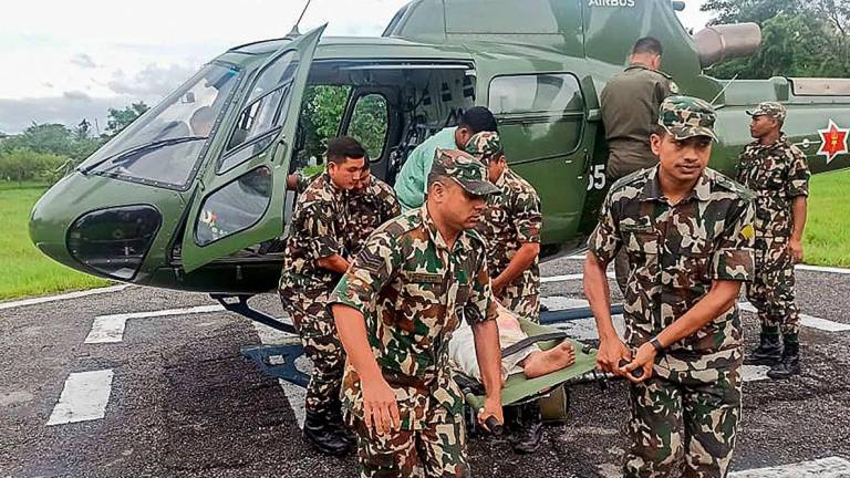 This handout photograph taken and released by Nepal’s Army on October 5, 2025 shows Army personnel carrying a landslide victim evacuated by a helicoper following heavy rain-triggered landslides and floods in Nepal. Landslides and floods triggered by heavy downpours in Nepal have killed at least 42 people, a disaster official said October 5 - AFP PHOTO / Nepal’s Army / - / HANDOUT