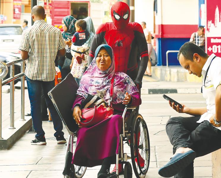 Spider-Man’ Ahmad Shakirin Mohd Zain strolling with his wife near the Komtar building in Penang, where the public and tourists can take a picture with him for a small fee — SUNPIX BY MASRY CHE ANI