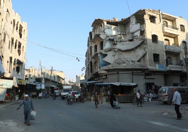 People walk near heavily damaged buildings in the rebel-held city of Idlib in northwestern Syria on September 16, 2019. — AFP