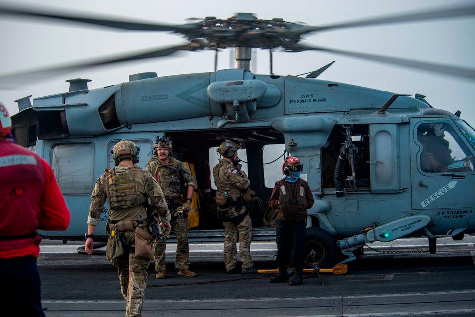 Sailors assigned to Explosive Ordnance Disposal Mobile Unit (EODMU) 5 board an MH-60S Sea Hawk helicopter, attached to the “Golden Falcons” of Helicopter Sea Combat Squadron (HSC) 12, are seen on the flight deck of aircraft carrier USS Ronald Reagan (CVN 76), in response to a call for assistance from the Mercer Street, a Japanese-owned Liberian-flagged tanker managed by Israeli-owned Zodiac Maritime, in the Arabian Sea July 30, 2021. Picture taken July 30, 2021. U.S. Navy/Handout via Reuters
