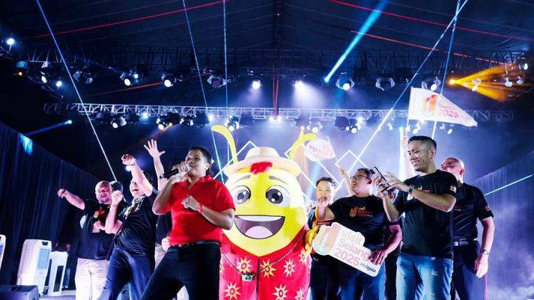 Aizat (in red) performing the official theme song, together with VSY 2025 mascot Spark the Firefly and other VIPs.