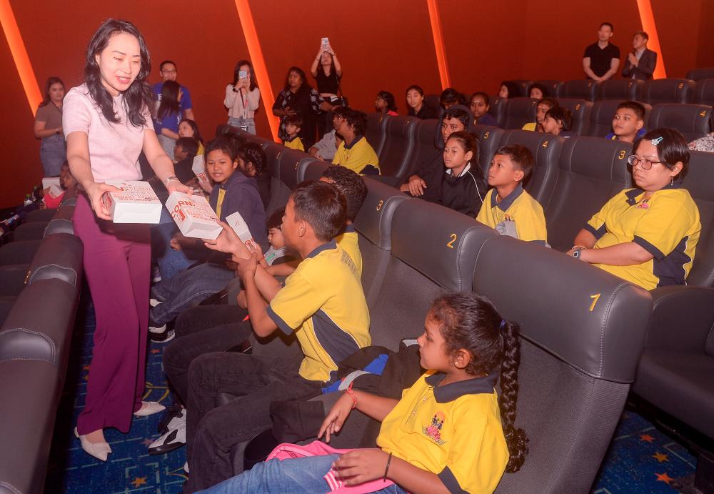 - Tan distributing popcorn to the children before the movie. – THESUNPIX