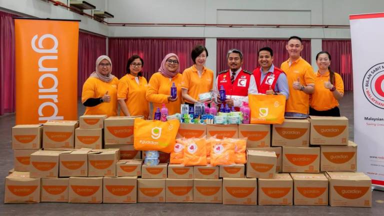 Guardian Malaysia senior manager of public relations and events Jennifer Wong (4th from left) handing over flood aid items to MRC secretary-general Hakim Hamzah (4th from right).