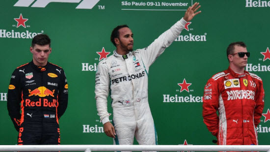 Lewis Hamilton celebrates as a rueful Max Verstappen looks on. — AFP