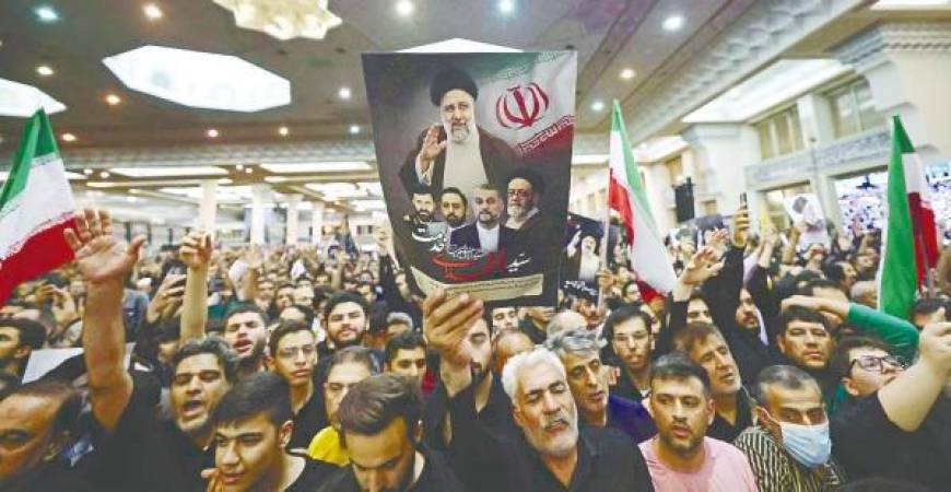 Mourners hold posters of Raisi during a funeral ceremony for him. – AFPpix