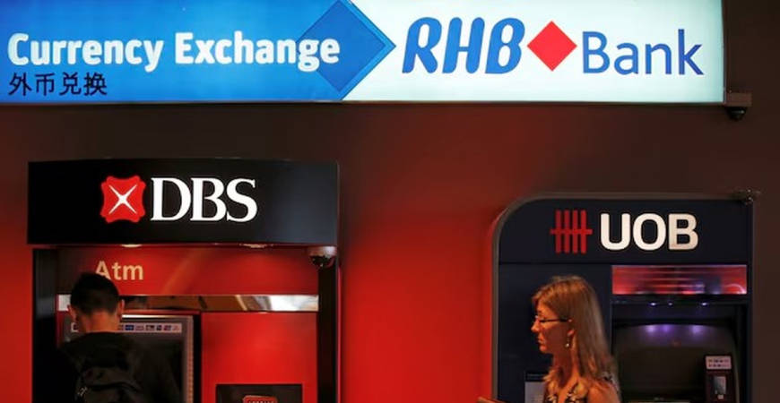 A man uses a DBS automated teller machine next to a United Overseas Banking (UOB) teller, near an RHB Capital Bhd currency exchange booth in Singapore January 5, 2016. - REUTERS