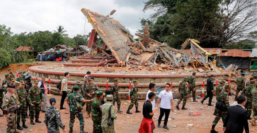 Military attaches and diplomats from 13 countries observe the implementation of the Cambodia–Thailand ceasefire agreement next to a destroyed building by the An Ses border checkpoint in Cambodia’s Preah Vihear province on July 30, 2025. - Chor Sokunthea / AFP