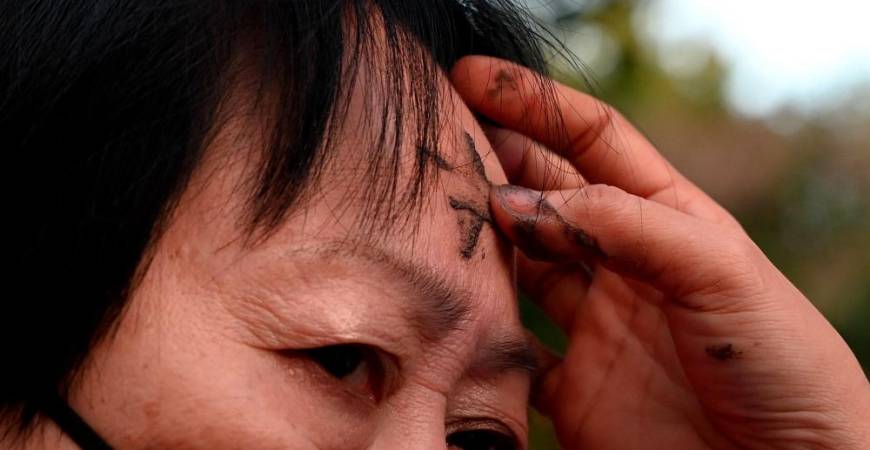 A woman receives ash as she attends a mass in observance of the Ash Wednesday at a church in Manila on February 14, 2024. - AFPPIX