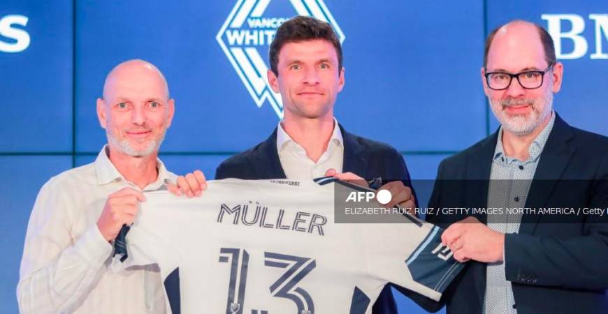 Thomas Müller poses with his jersey alongside Jesper Sørensen (L) Whitecaps FC head coach and Axel Schuster, Whitecaps FC CEO &amp; sporting director during a press conference at TELUS Garden on August 14, 2025 in Vancouver, British Columbia. - Elizabeth Ruiz Ruiz/Getty Images/AFPPIX