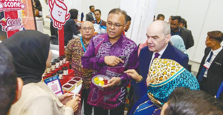 Isham and Kuala Lumpur Convention Centre general manager John Burke (right) testing local food products at a booth at the International Café and Beverage Show 2025 and MyFood 2025 launch today.
