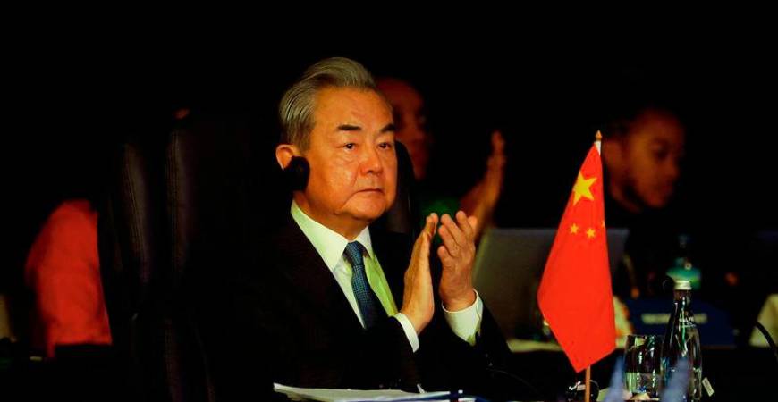 China's Foreign Minister Wang Yi (C) reacts as unseen South African President Cyril Ramaphosa delivers the keynote address at the welcome ceremony during the G20 Foreign Minister Meeting at the Nasrec Expo Centre in Johannesburg on February 20, 2025. - AFPPIX