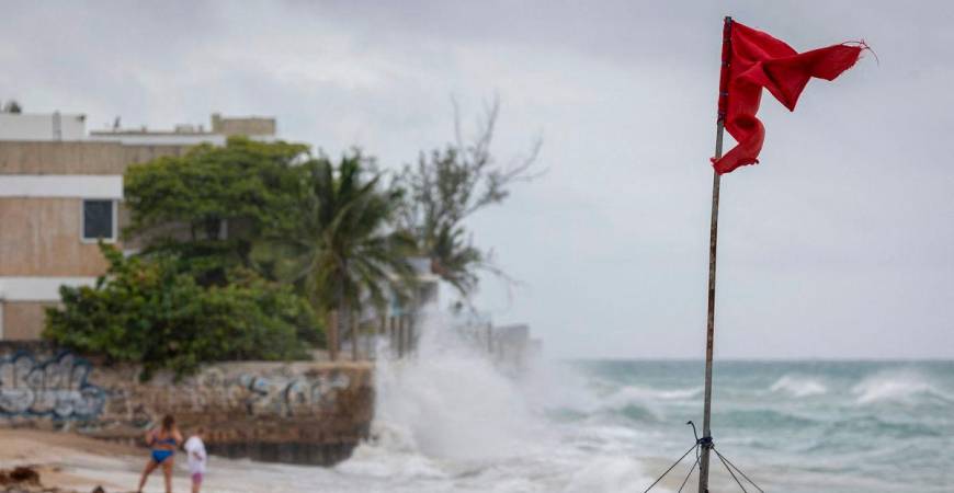 A ripped red flag warning of rip current waves as Category 5 Hurricane Erin approaches in San Juan, Puerto Rico, on August 16, 2025. Hurricane Erin on Saturday strengthened to a “catastrophic” Category 5 storm as it barrelled towards the Caribbean, with weather officials warning of possible flash floods and landslides. (Photo by Ricardo ARDUENGO / AFP)