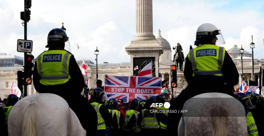 Mounted police officers look on as a Union Jack flag is displayed by supporters of British far-right activist Tommy Robinson whose real name is Stephen Yaxley-Lennon, during a ‘Free speech’ march, in central London on September 13, 2025. (Photo by CARLOS JASSO / AFP)