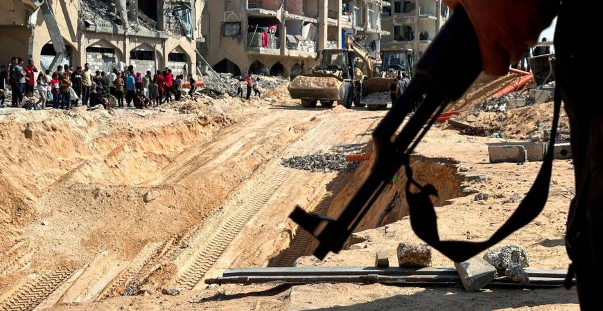 Hamas militant stands guard, as heavy machinery operates at the site where searches are underway for the bodies of hostages killed after being seized by Hamas during the October 7, 2023 attack, amid a ceasefire between Israel and Hamas, in Khan Younis, southern Gaza Strip, October 17, 2025. - REUTERSPIX
