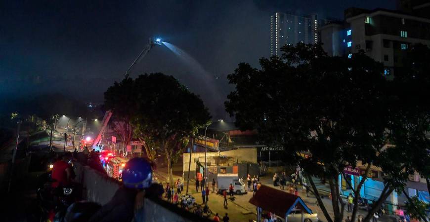 Anggota Jabatan Bomba dan Penyelamat Malaysia (JBPM) giat memadamkan sisa kebakaran yang menyebabkan beberapa buah lot kedai dan rumah di Pantai Dalam, Kuala Lumpur terbakar dalam kejadian malam tadi. - fotoBERNAMA