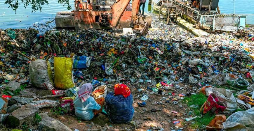 Ragpickers sit near the plastic waste gathered at Hussain Sagar lake in Hyderabad on September 14, 2024. - AFPPIX