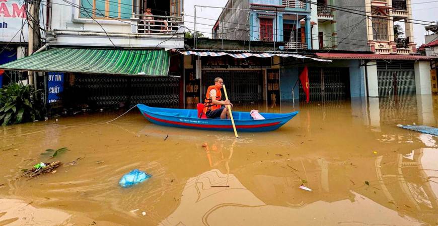 A man rows a canoe through waters past buildings in That Khe commune flooded after heavy rains caused by Typhoon Matmo in Lang Son province on October 8, 2025. (Photo by Anh TUC / AFP)