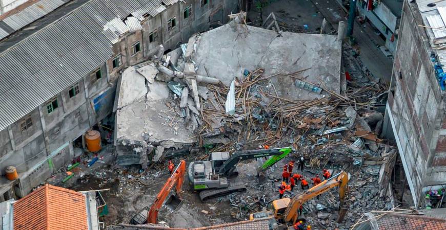 An aerial view shows rescuers searching for victims at the Al Khoziny Islamic boarding school in Sidoarjo, East Java, on October 5, 2025, after a multi-story building at the school collapsed during prayers, killing at least 37 people, with 26 others still missing, according to an official. (Photo by Dicky Bisinglasi / AFP)