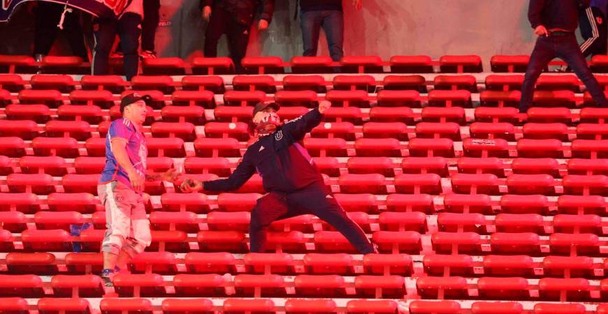 A fan of Universidad de Chile prepares to throw a stone during the interruption of the Copa Sudamericana round of 16 second leg football match between Argentina’s Independiente and Chile’s Universidad de Chile at the Libertadores de America stadium in Avellaneda, Buenos Aires province, Argentina on August 20, 2025. (Photo by Alejandro PAGNI / AFP)