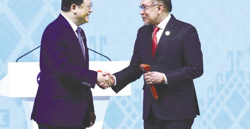 Prime Minister Datuk Seri Anwar Ibrahim holds the ceremonial gavel as he shakes hands with Laos Prime Minister Sonexay Siphandone, who handed over his country’s chairmanship to Malaysia. – REUTERSPIC