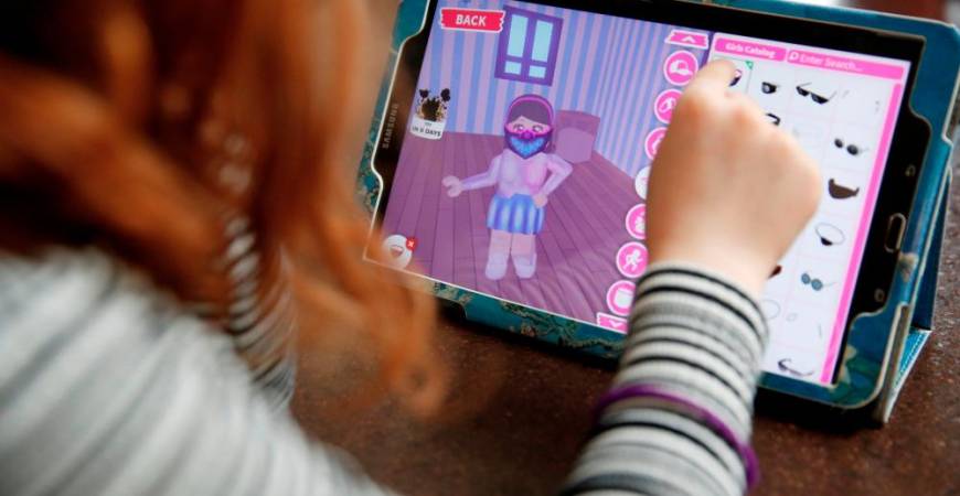 FILE PHOTO: Alice Wilkinson (7) adds a face mask to her character on the game ‘Roblox’ at her home in Manchester, as the spread of the coronavirus disease (COVID-19) continues, Manchester, Britain, April 5, 2020. REUTERS/Phil Noble/File Photo