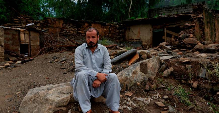 Aziz Ahmed, 45, a school teacher, sits with a damaged house in the background following a storm that caused heavy rains and flooding, in Bayshonai Kalay, Buner district, Khyber Pakhtunkhwa province, Pakistan, August 17, 2025. REUTERS/Akhtar Soomro