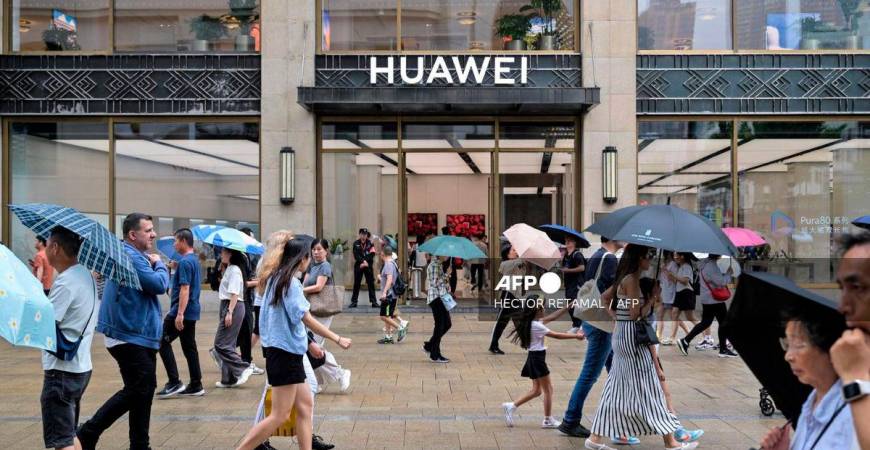 For representational purposes only: People walk past the Huawei Shanghai flagship store in the Huangpu district in Shanghai, on June 23, 2025. (Photo by Hector RETAMAL / AFP)