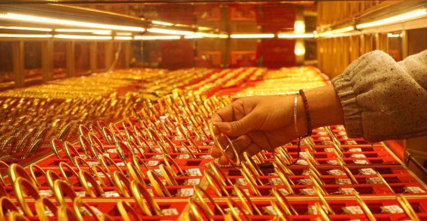 A shop assistant displays gold bangles for sale at a gold shop in Hangzhou, in eastern China’s Zhejiang province on April 22, 2025.