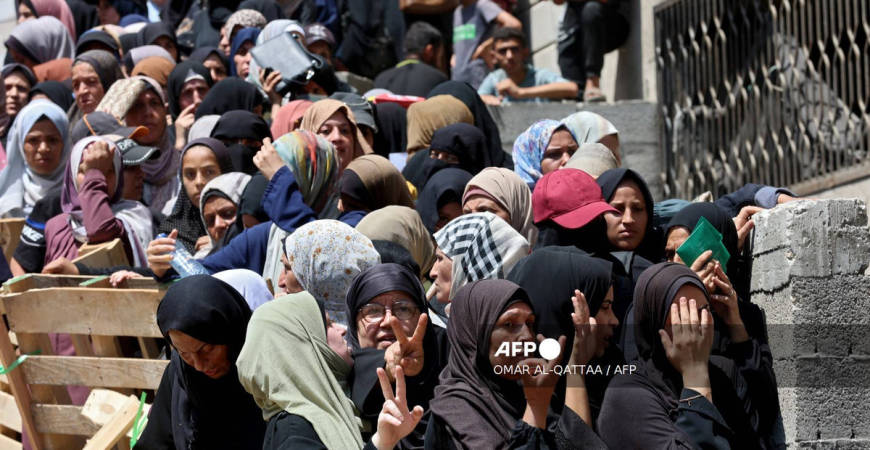 Palestinian women flash the V for victory sign as they line up to receive bags of flour at a UN World Food Programme (WFP) warehouse on Al-Jalaa street in Gaza City, in the central Gaza Strip on July 12, 2025. - AFP