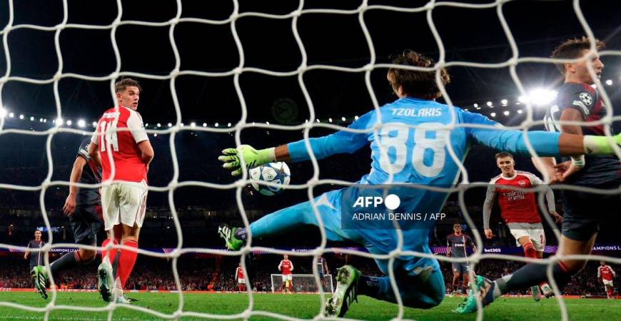 Olympiakos' Greek goalkeeper #88 Konstantinos Tzolakis reaches to save a shot from Arsenal's Norwegian midfielder #08 Martin Odegaard during the UEFA Champions League, league phase football match between Arsenal and Olympiacos at the Emirates Stadium in north London on October 1, 2025. - AFP