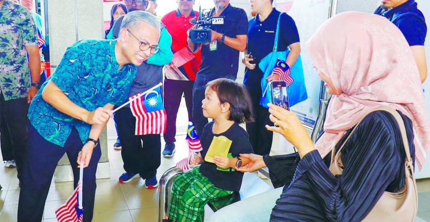 Fahmi waving the national flag with visitors at the launch event yesterday. – Adib Rawi Yahya/theSun