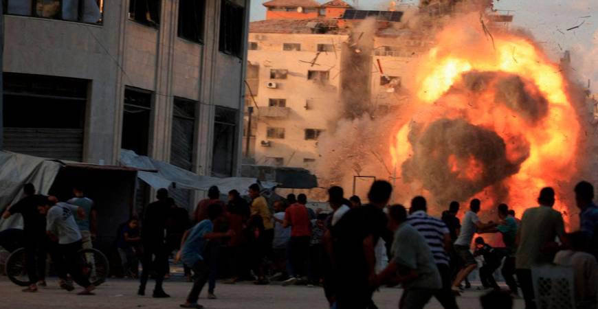 Palestinians react, as smoke and flames rise while a residential building collapses after an Israeli air strike, in Gaza City, September 7, 2025. - REUTERS