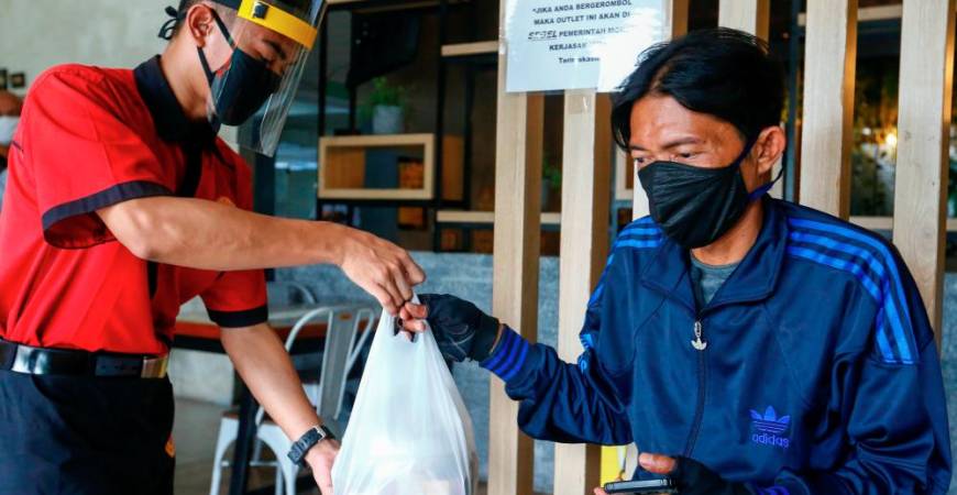 A waiter wearing a face shield and a protective mask hands takeaway food to a man at a restaurant, as the Indonesian capital kicks off a two-week “transitional” period of easing restrictions, after the pace of coronavirus disease (COVID-19) infections slowed over the last two weeks, in Jakarta, Indonesia, October 12, 2020. REUTERS/Ajeng Dinar Ulfiana