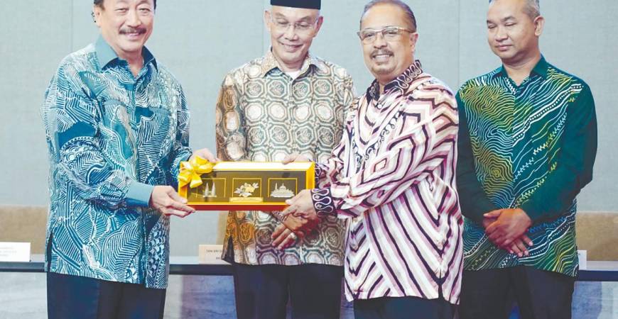 Tan (left) presenting a token of appreciation to Syed Tajul Arif after the MoU signing between Berjaya Land and Impianan Utara, witnessed by Mohd Shukri Ramli (second left) and MBI Perlis acting CEO Ahmad Hishamudin Johari. – AMIRUL SYAFIQ/THESUN