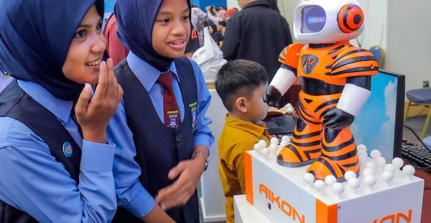 FUTURE IN FOCUS ... Students marvel at an AI robot showcased at the AI Grand Prix 2025 Conference yesterday. The event, launched by Fahmi, discussed AI’s impact on communication, media and the digital landscape. – ADIB RAWI YAHYA/THESUN