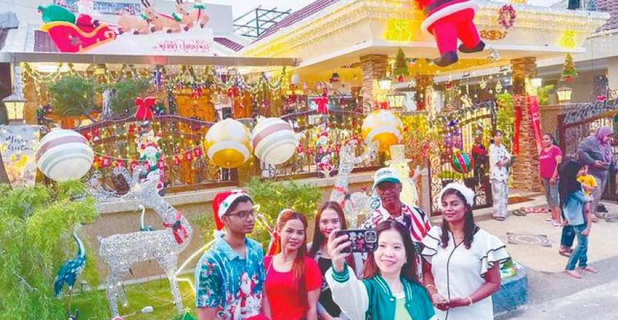 Visitors pose with house owner Charles Dorney (wearing cap), his wife Christe Samasundram (right) and son Dohnaven. – MASRY CHE ANI/THESUN