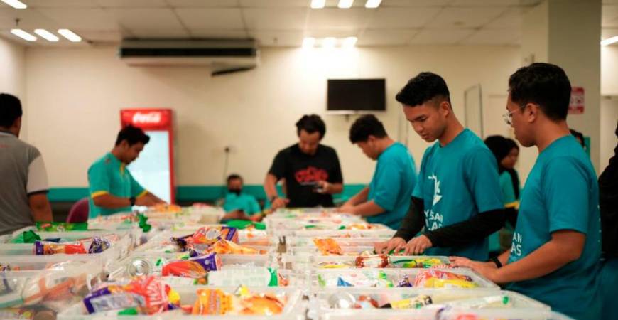 Volunteers from Lotus’s Malaysia and Coca-Cola packing food boxes for families in need.