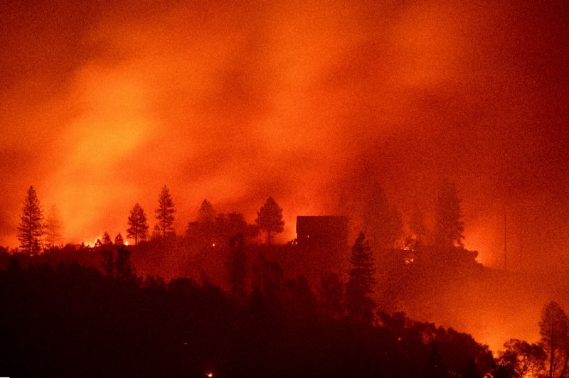 Flames from the Camp Fire burn near a home atop a ridge near Big Bend, California. — AFP
