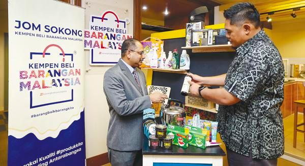 $!Rohaizi (left) looks at local products during an interview at his office in Putrajaya.–Bernamapix