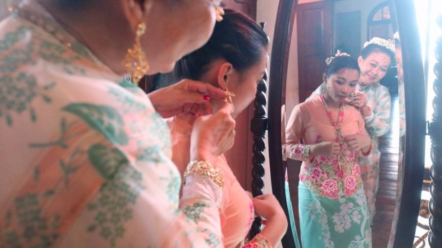 Lilian Tong (L) assisting Cheng Hooi Yen to wear the Baba Nyonya jewellery. — Sunpix by Masry Che Ani