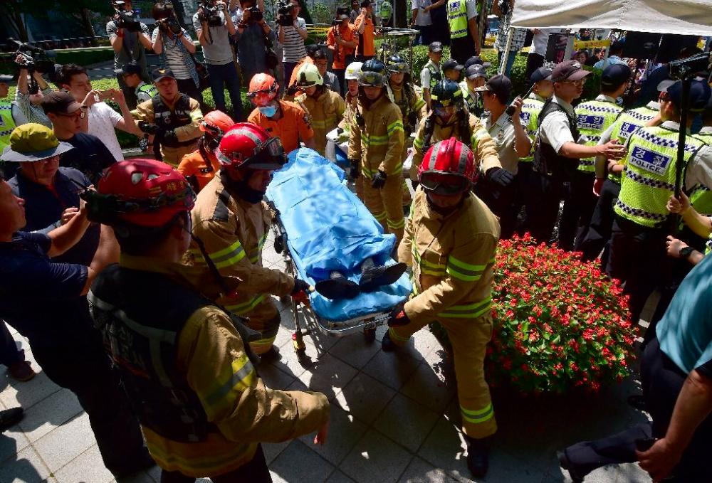 South Korean fire fighters take away a man (C, on stretcher) who set himself on fire outside the Japanese embassy in Seoul on August 12, 2015 during a protest to demand Tokyo’s apology for forcing women into military brothels during World War II. — AFP