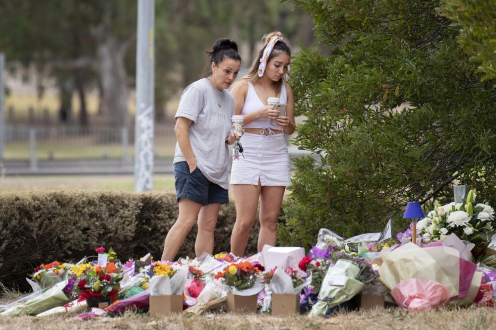 Two women stand at a floral tribute, Friday, Jan. 18, 2019, at the scene where the body of Israeli student Aiia Maasarwe was found earlier in the week in Melbourne, Australia.