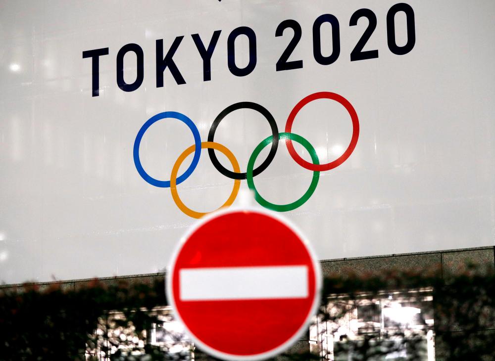 A banner for the upcoming Tokyo 2020 Olympics is seen behind a traffic sign, following an outbreak of the coronavirus disease (Covid-19), in Tokyo, Japan, March 23, 2020. - Reuters