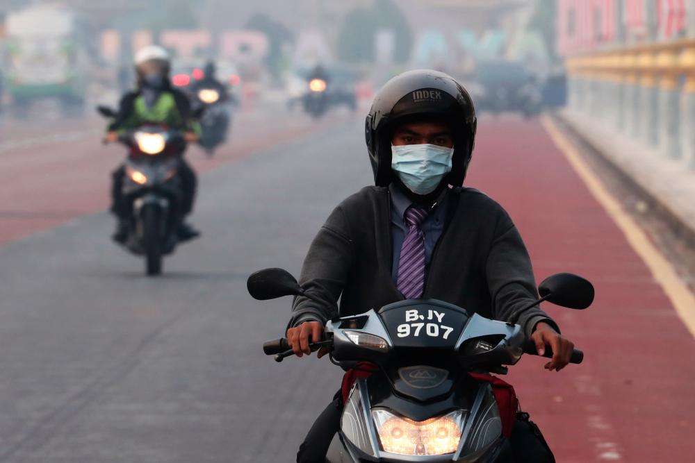 A man rides on a motorcycle in the haze in Putrajaya, Malaysia, September 17, 2019. - Reuters