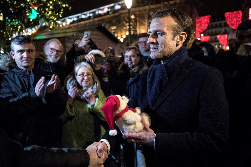 French President Emmanuel Macron receives a gift from a visitor as he visits the Christmas market in Strasbourg Dec 14, 2018. — Reuters