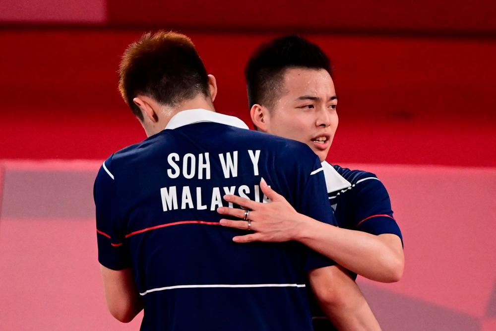 Malaysia's Soh Wooi Yik (L) and Malaysia's Aaron Chia hug after winning their men's doubles badminton quarter final match against Indonesia's Kevin Sanjaya Sukamuljo and Indonesia's Marcus Fernaldi Gideon during the Tokyo 2020 Olympic Games at the Musashino Forest Sports Plaza in Tokyo on July 29, 2021. AFPPIX