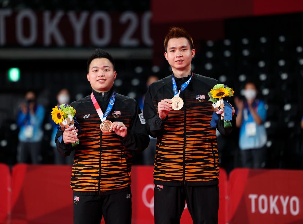 National men's badminton duo Aaron Chia (right) and Soh Wooi Yik (left) posing with the first bronze medal that they won after beating the Indonesian team at the Tokyo 2020 Olympic Games at Mushashino Sports Plaza today. — Bernama